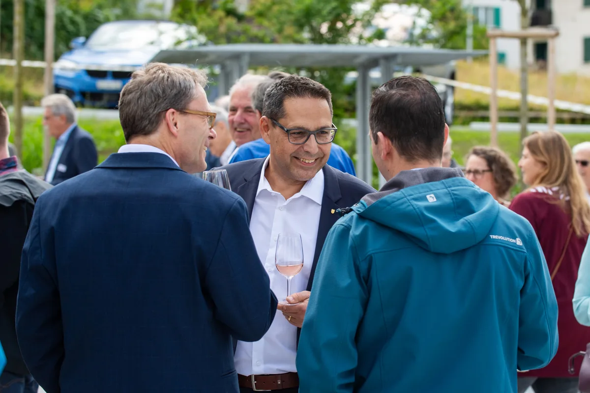 Mehrere Menschen stehen zusammen und reden und lachen. 